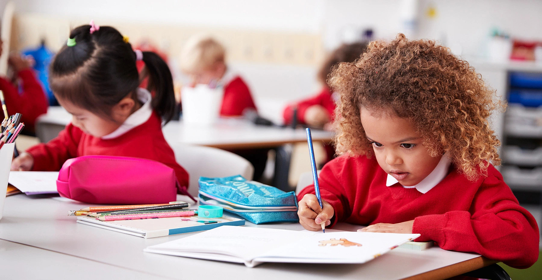 Two young students writing in their notebooks