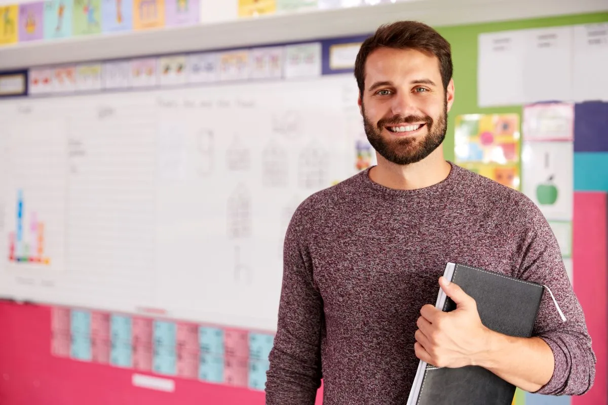 Supply teacher holding documents in a uk classroom in front of a white board