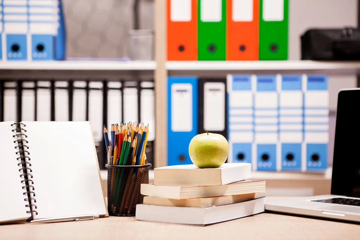 supply teachers books and apple in a classroom